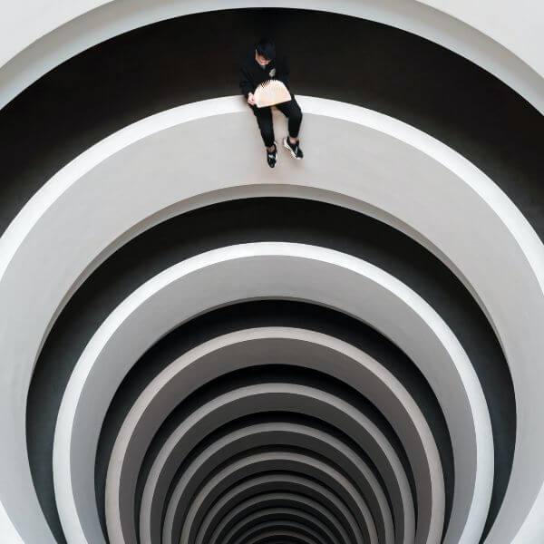 man sitting on spiral wall while flicking through book pages